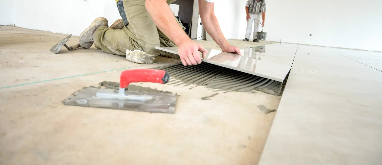 Handwerker arbeiten in einem Neubau, verlegen Fliesen, renovieren